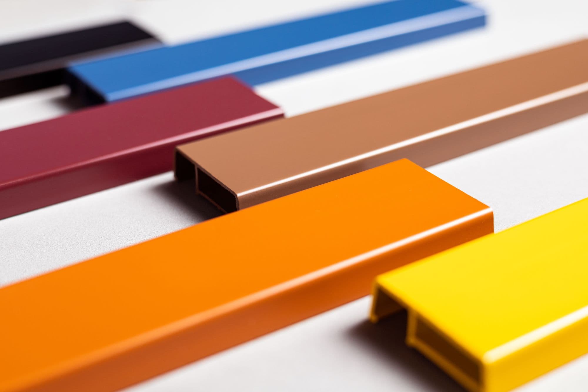Perfis de PVC pintados em laranja, amarelo, azul, bordô e cobre